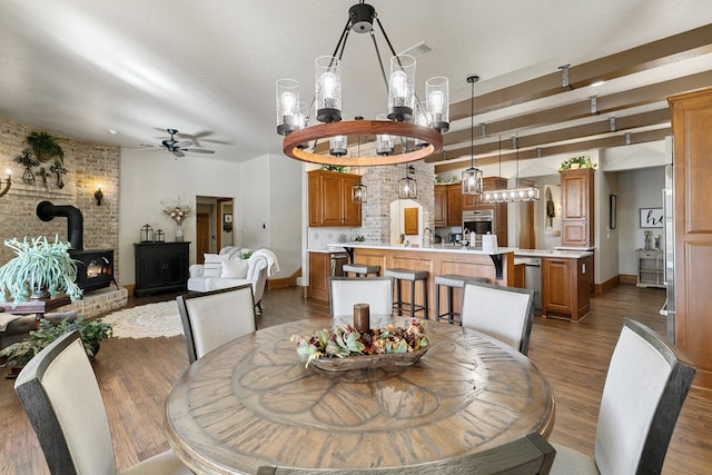 dining space featuring a wood stove, ceiling fan with notable chandelier, and dark hardwood / wood-style floors