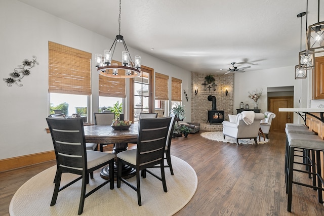 dining room with ceiling fan with notable chandelier, dark hardwood / wood-style floors, and a wood stove