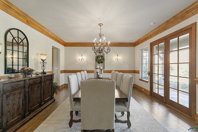 dining area featuring a notable chandelier, wood-type flooring, ornamental molding, and french doors