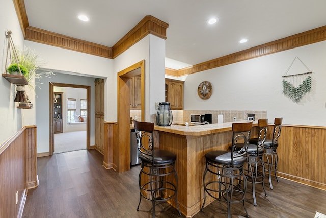 bar with tasteful backsplash, crown molding, dark wood-type flooring, tile countertops, and wood walls