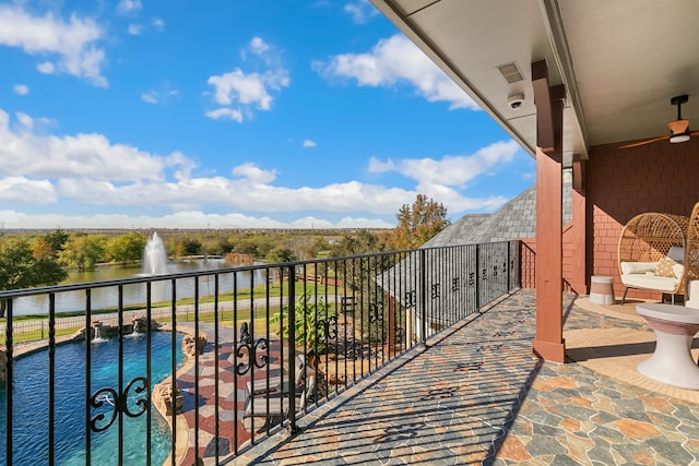 balcony featuring ceiling fan, a water view, and pool water feature