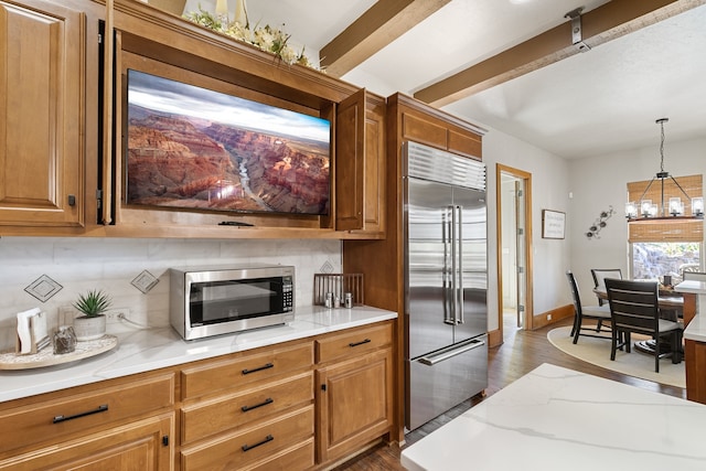 kitchen featuring backsplash, light stone counters, stainless steel appliances, dark wood-type flooring, and pendant lighting