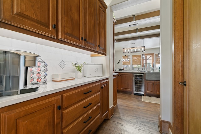 bar with beverage cooler, light stone counters, backsplash, hardwood / wood-style floors, and decorative light fixtures