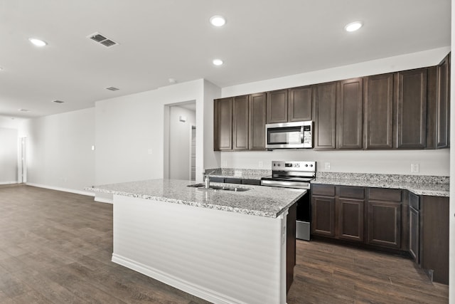 kitchen featuring dark wood-type flooring, sink, stainless steel appliances, and a kitchen island with sink