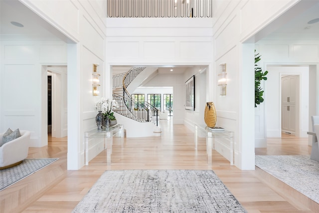 entrance foyer featuring light wood-type flooring and a towering ceiling