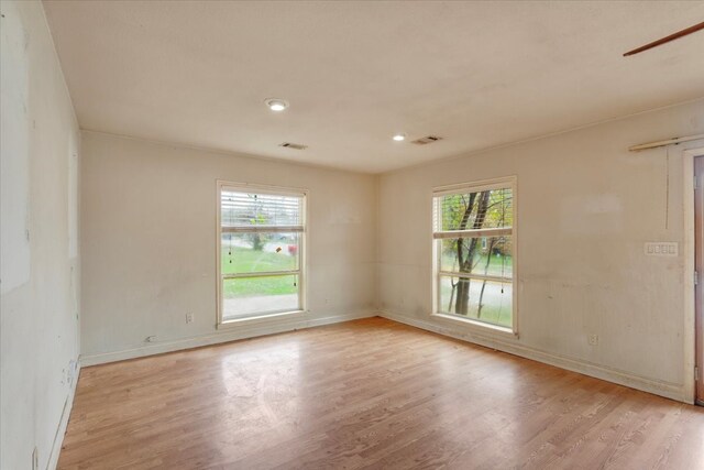 spare room featuring light hardwood / wood-style floors and a healthy amount of sunlight