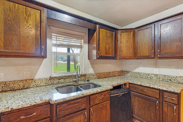 kitchen featuring light stone countertops, sink, dishwasher, and a textured ceiling