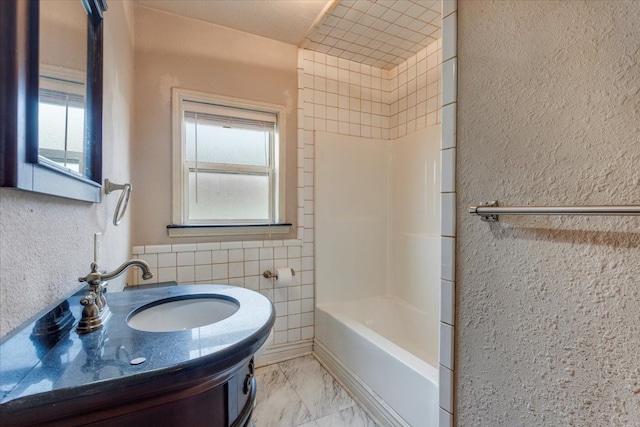 bathroom featuring vanity, tile walls, and bathtub / shower combination