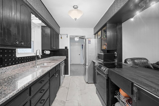 kitchen featuring dark stone counters, sink, ceiling fan, tasteful backsplash, and stainless steel appliances