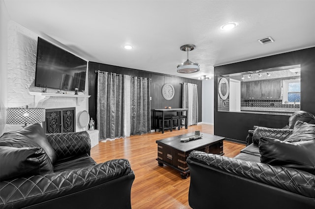 living room featuring a brick fireplace and light hardwood / wood-style flooring