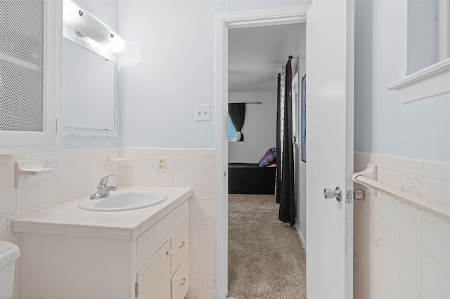 bathroom with vanity, toilet, and tile walls