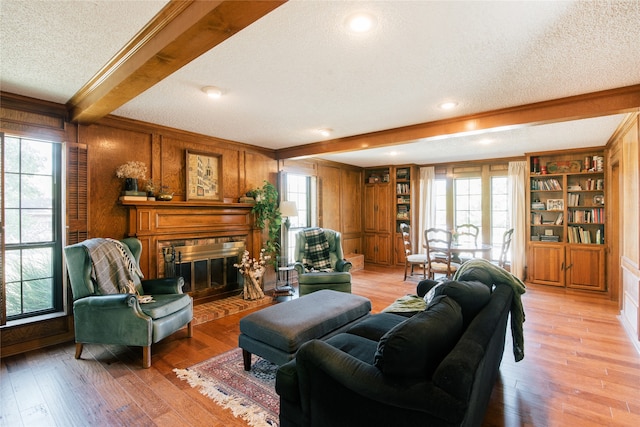 living room with beamed ceiling, plenty of natural light, a textured ceiling, and light hardwood / wood-style flooring