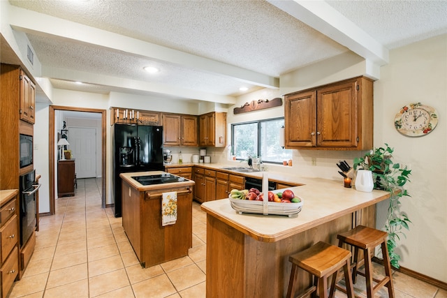 kitchen with kitchen peninsula, a kitchen breakfast bar, black appliances, beam ceiling, and a center island