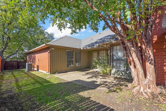 rear view of house featuring a lawn and central air condition unit