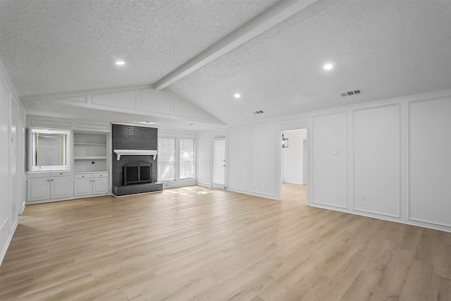 unfurnished living room with a brick fireplace, vaulted ceiling with beams, a textured ceiling, and light wood-type flooring