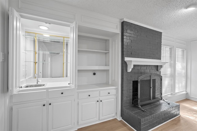 living room featuring a textured ceiling, a fireplace, light hardwood / wood-style floors, and sink