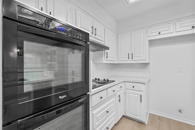 kitchen featuring black appliances, white cabinetry, a textured ceiling, and light hardwood / wood-style flooring