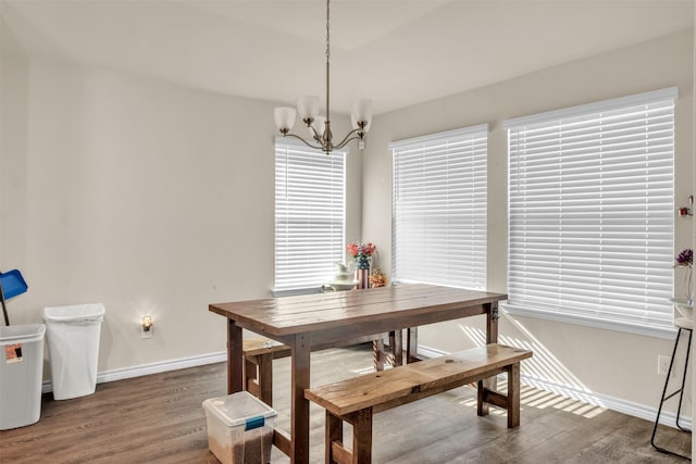 dining area with dark hardwood / wood-style floors and an inviting chandelier