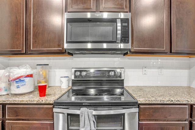 kitchen featuring decorative backsplash, appliances with stainless steel finishes, dark brown cabinetry, and light stone counters