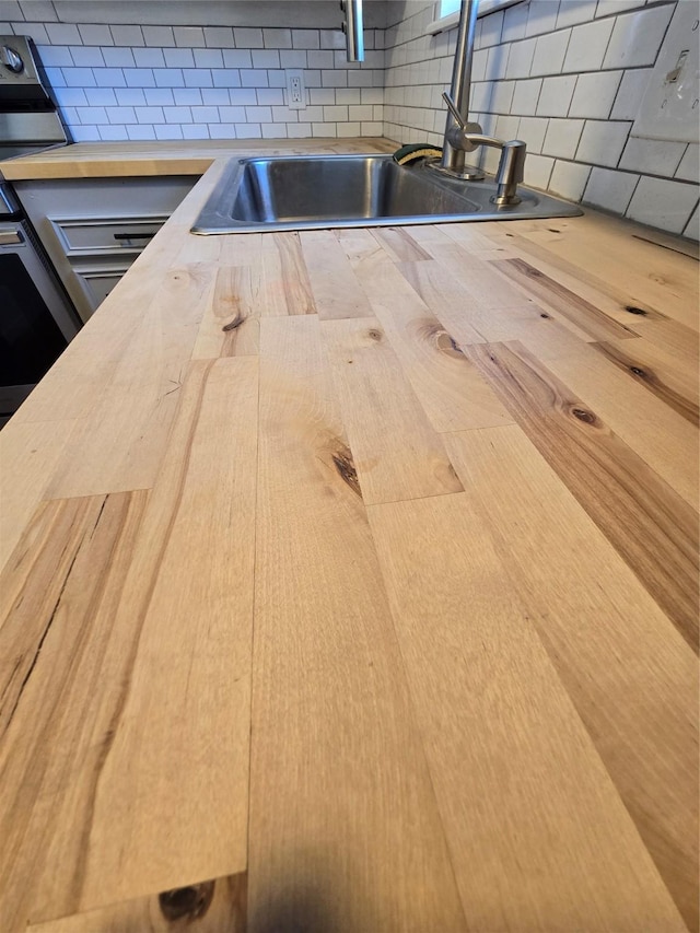 details featuring sink, wood counters, and tasteful backsplash