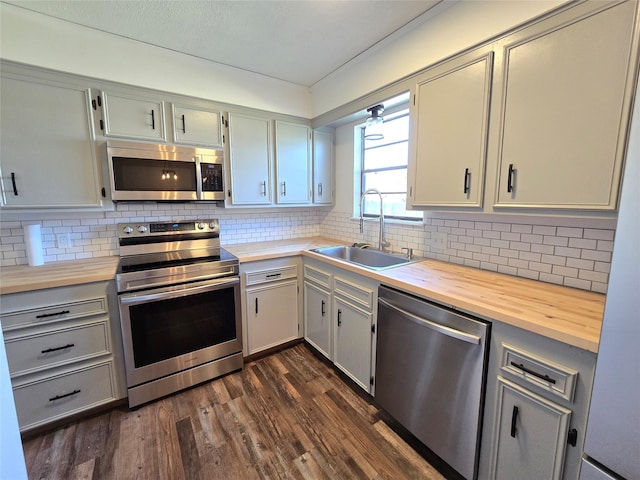 kitchen with sink, stainless steel appliances, backsplash, and butcher block counters