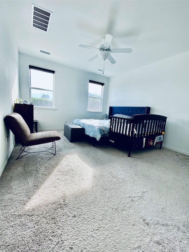 carpeted bedroom featuring multiple windows and ceiling fan