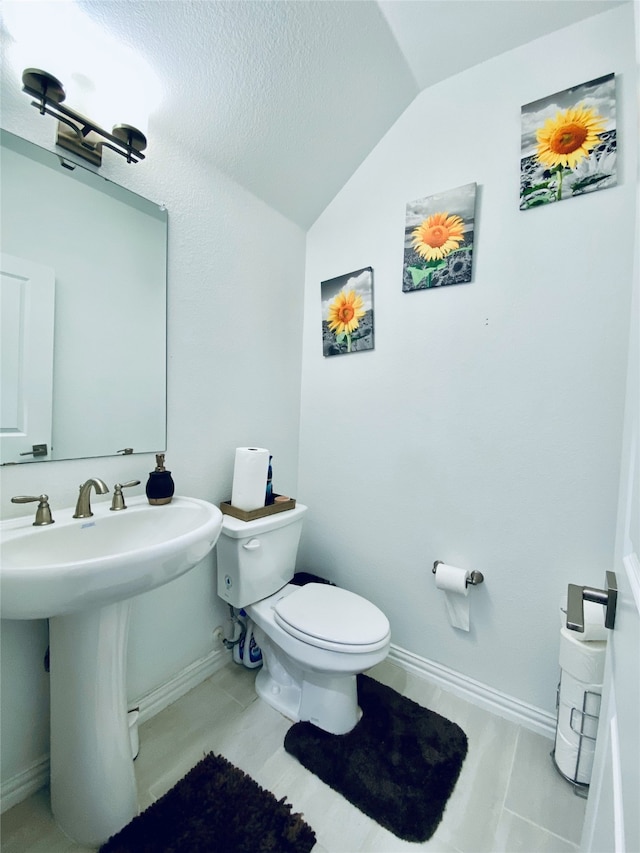 bathroom featuring toilet, tile patterned floors, vaulted ceiling, and sink