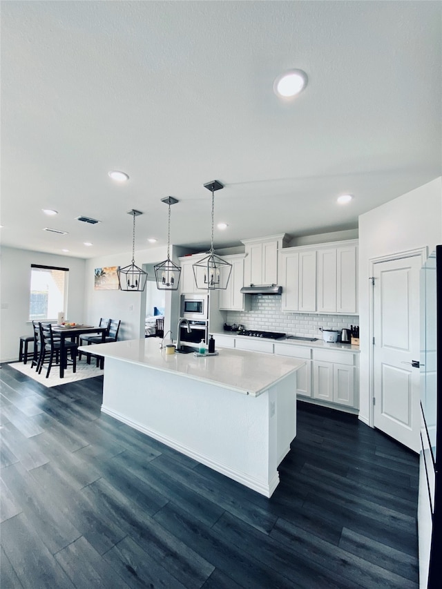 kitchen with white cabinets, hanging light fixtures, dark wood-type flooring, and a kitchen island with sink