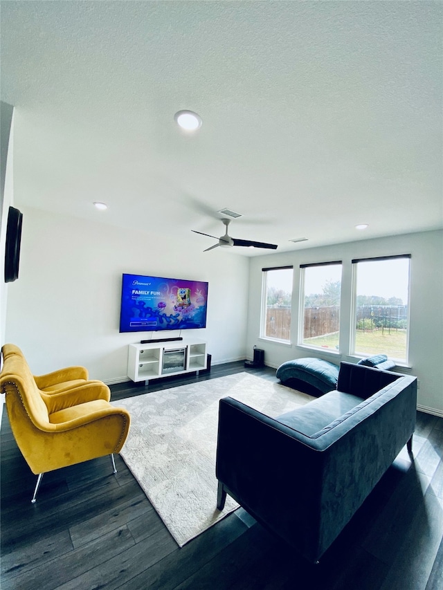 living room featuring dark hardwood / wood-style floors, ceiling fan, and a textured ceiling