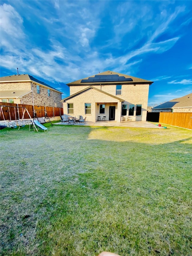 rear view of house featuring a yard, a patio, solar panels, and a trampoline