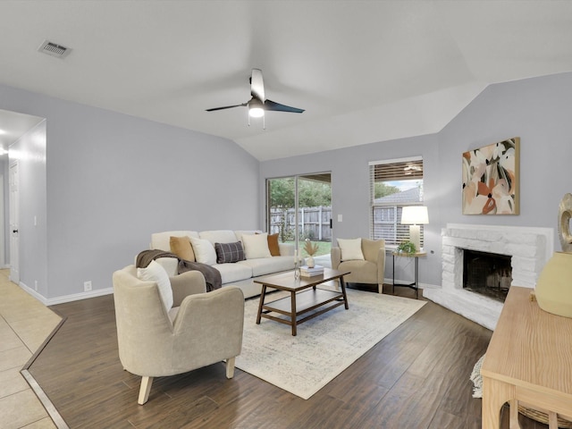 living room with lofted ceiling, ceiling fan, dark hardwood / wood-style floors, and a stone fireplace