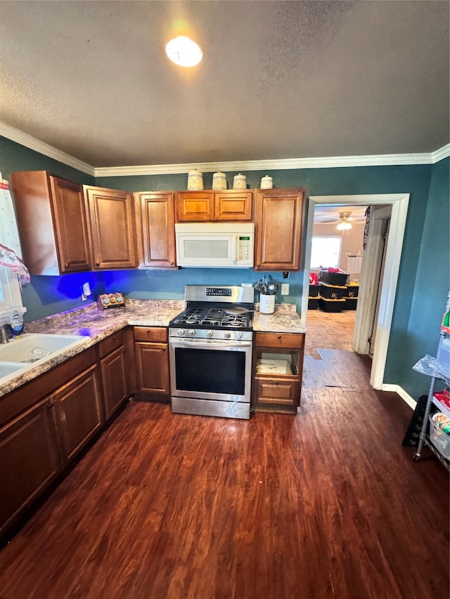 kitchen featuring sink, gas stove, crown molding, and dark wood-type flooring