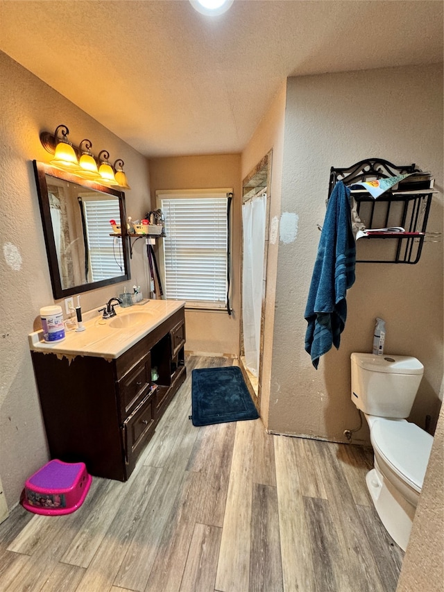 bathroom featuring hardwood / wood-style floors, vanity, toilet, walk in shower, and a textured ceiling