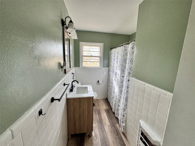 bathroom with a shower with shower curtain, vanity, hardwood / wood-style flooring, and tile walls