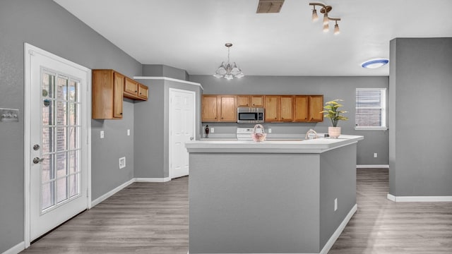 kitchen featuring stainless steel microwave, visible vents, light countertops, light wood-style flooring, and an inviting chandelier