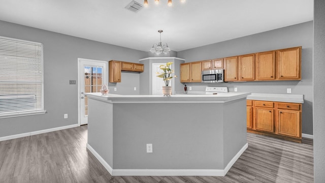 kitchen featuring stainless steel microwave, baseboards, light countertops, and visible vents