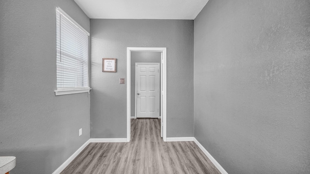 hall with wood finished floors, baseboards, and a textured wall