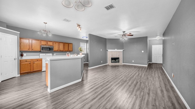 kitchen featuring visible vents, white range with electric cooktop, stainless steel microwave, wood finished floors, and a fireplace