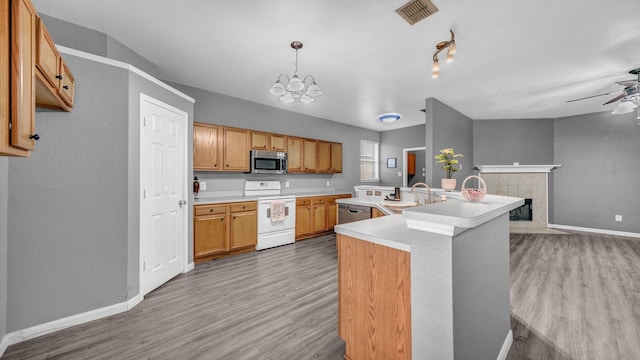 kitchen featuring visible vents, a sink, a tile fireplace, stainless steel appliances, and light wood-style floors