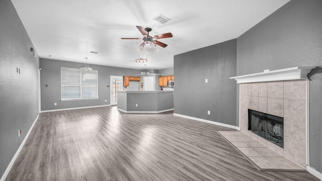 unfurnished living room featuring ceiling fan, baseboards, wood finished floors, and a tile fireplace