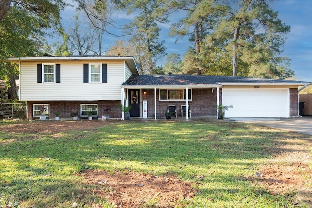 tri-level home with covered porch, a garage, and a front lawn