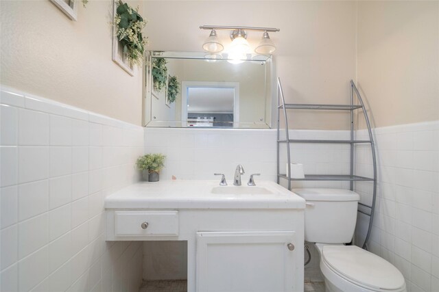 bathroom featuring tile patterned floors, vanity, tile walls, and toilet