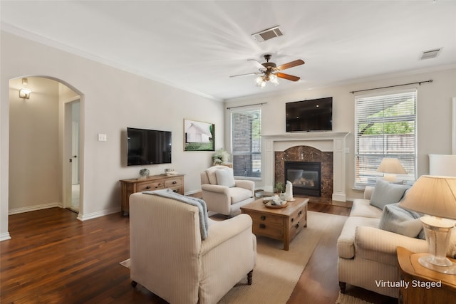 living room with dark hardwood / wood-style flooring, ceiling fan, crown molding, and a premium fireplace