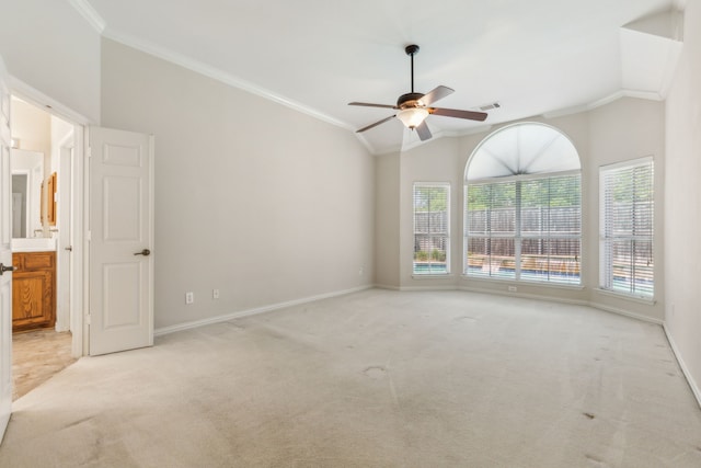 empty room featuring light carpet, vaulted ceiling, ceiling fan, and crown molding