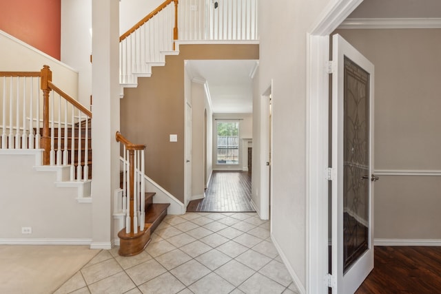 foyer entrance with light tile patterned floors and ornamental molding