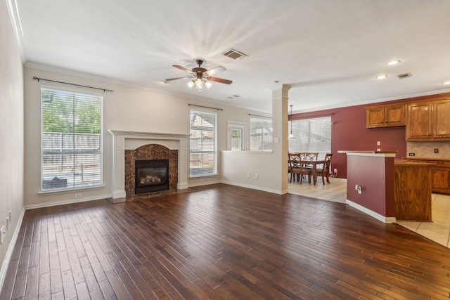 unfurnished living room with ceiling fan, dark hardwood / wood-style flooring, ornamental molding, and a fireplace