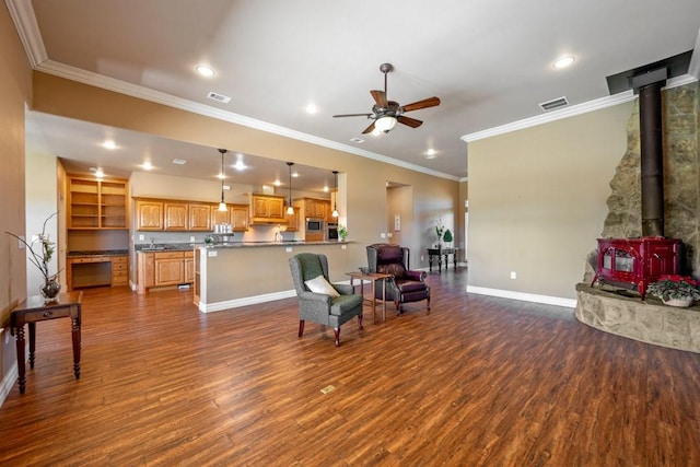 living room featuring dark wood-type flooring, ceiling fan, crown molding, and a wood stove