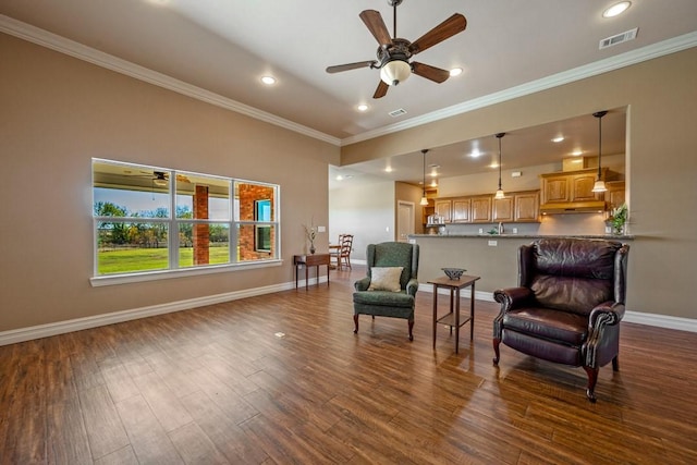 living area with crown molding, dark wood finished floors, a ceiling fan, visible vents, and baseboards