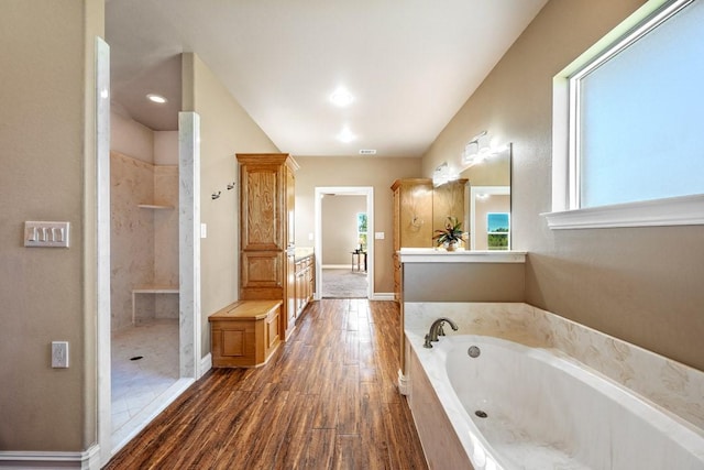 bathroom with vanity, hardwood / wood-style flooring, and plus walk in shower