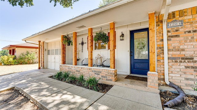 view of exterior entry with a porch and a garage